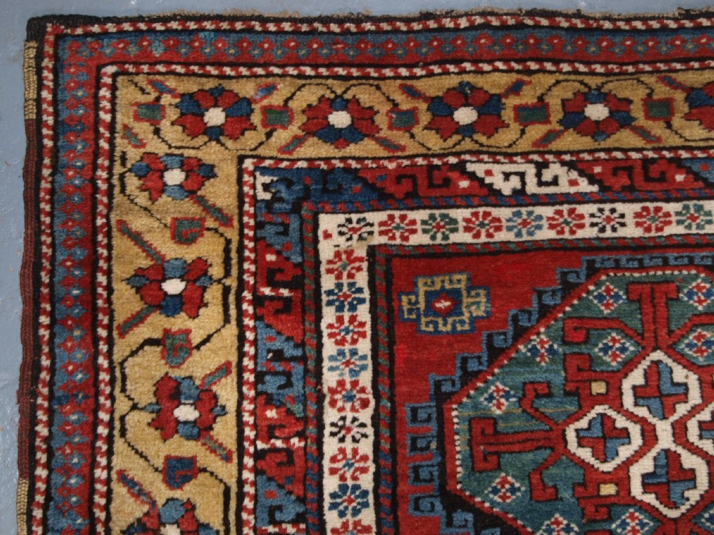 An antique South Caucasian Karabagh long rug featuring five large geometric medallions down a red central field framed by yellow floral and geometric borders. View VI