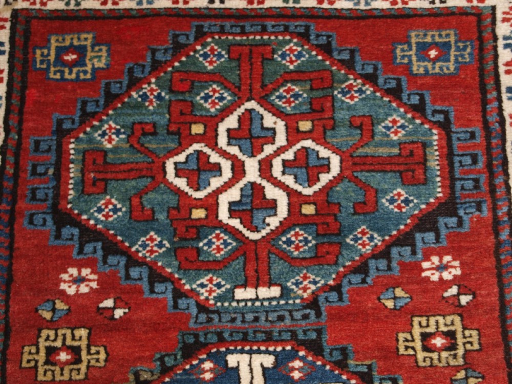An antique South Caucasian Karabagh long rug featuring five large geometric medallions down a red central field framed by yellow floral and geometric borders. View VIII
