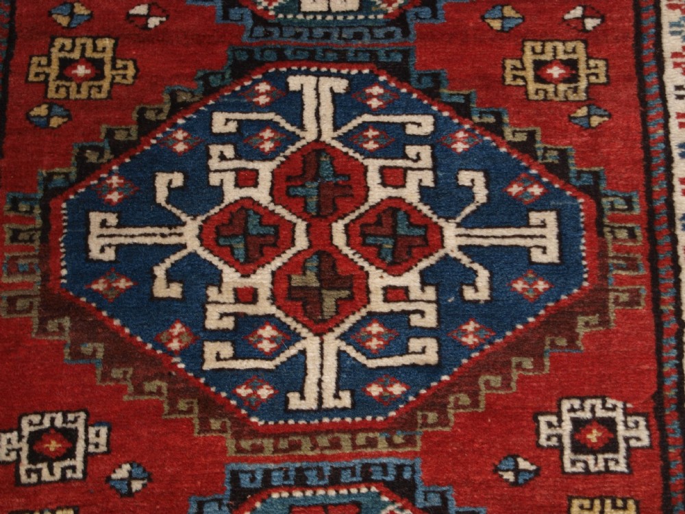 An antique South Caucasian Karabagh long rug featuring five large geometric medallions down a red central field framed by yellow floral and geometric borders. View IX
