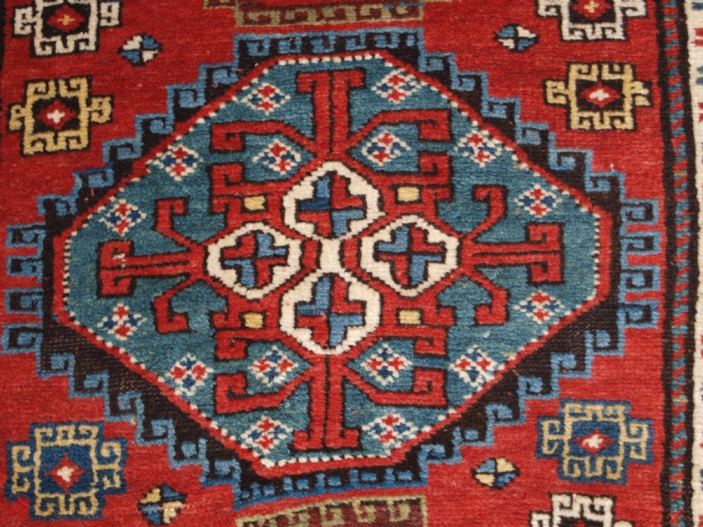 An antique South Caucasian Karabagh long rug featuring five large geometric medallions down a red central field framed by yellow floral and geometric borders. View XI