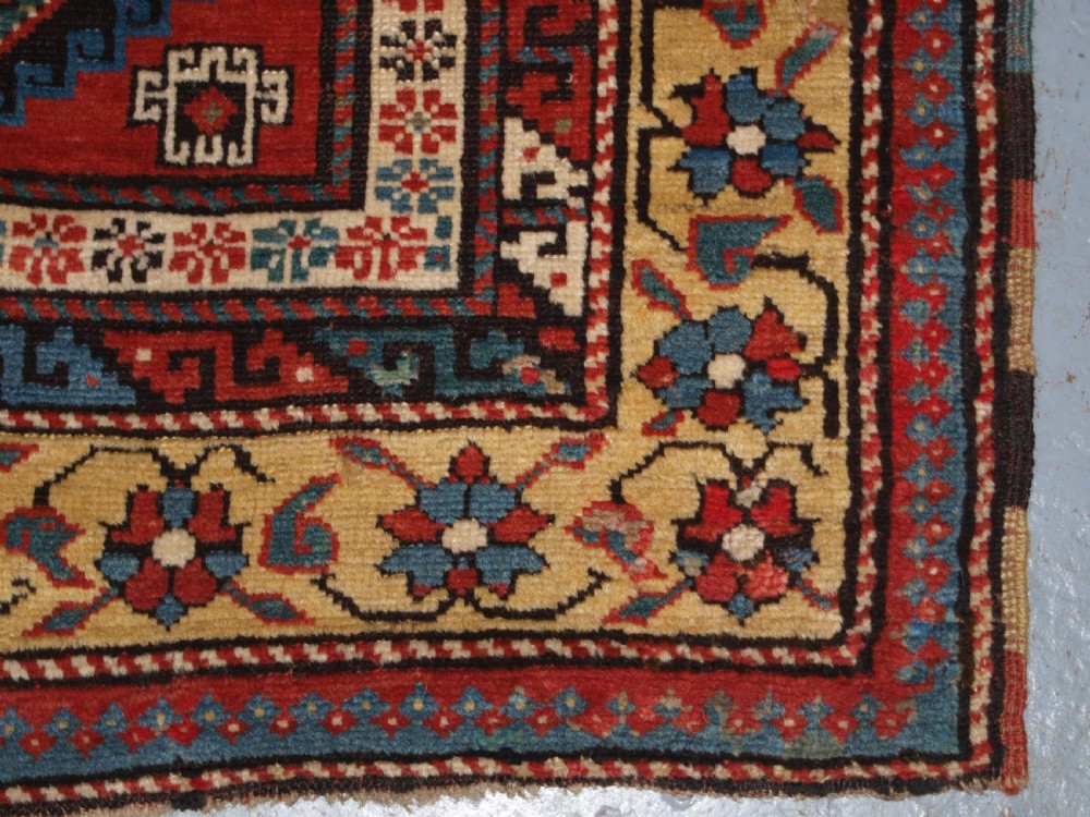 An antique South Caucasian Karabagh long rug featuring five large geometric medallions down a red central field framed by yellow floral and geometric borders. View XII