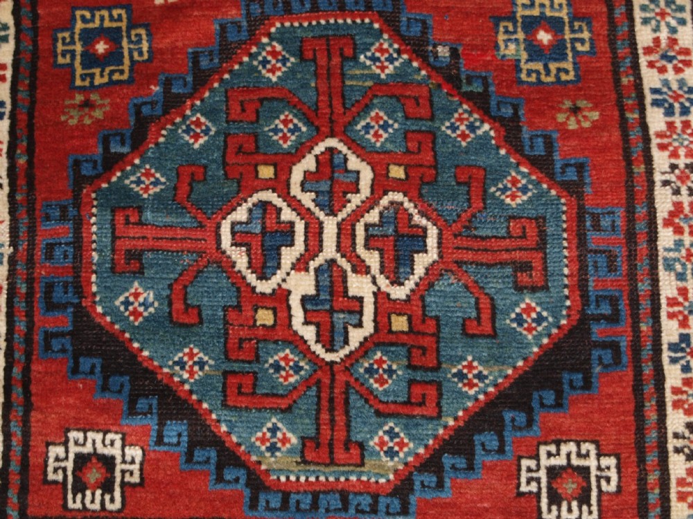 An antique South Caucasian Karabagh long rug featuring five large geometric medallions down a red central field framed by yellow floral and geometric borders. View XIII