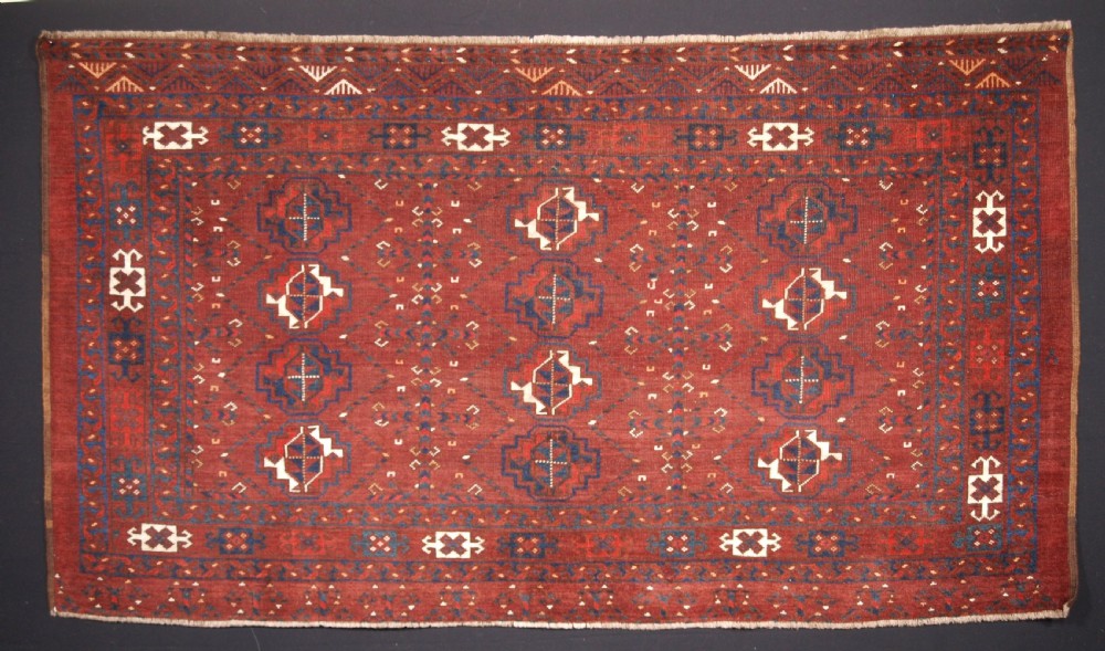 A rectangular hand-knotted antique Ersari Turkmen wool rug featuring twelve octagonal gul motifs on a deep red field with geometric borders.
