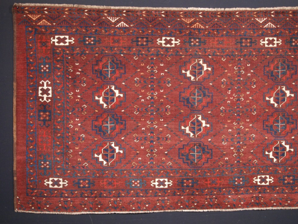 A rectangular hand-knotted antique Ersari Turkmen wool rug featuring twelve octagonal gul motifs on a deep red field with geometric borders. View II