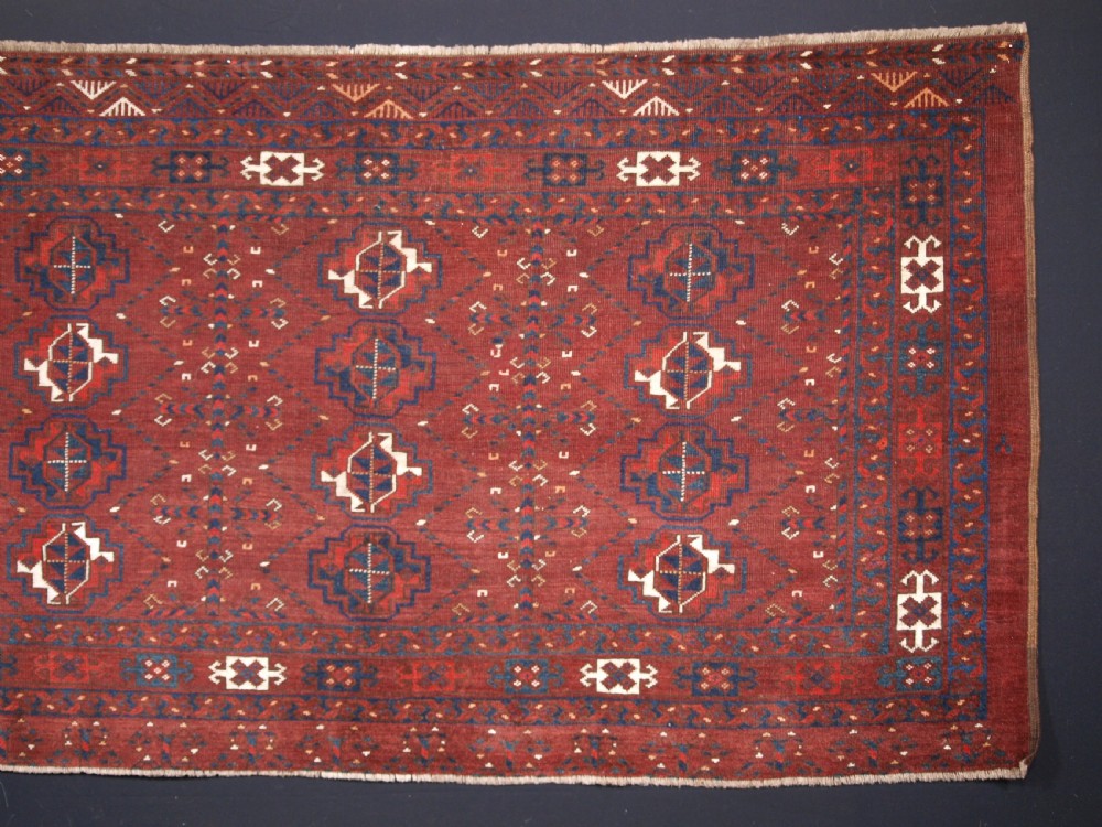 A rectangular hand-knotted antique Ersari Turkmen wool rug featuring twelve octagonal gul motifs on a deep red field with geometric borders. View III