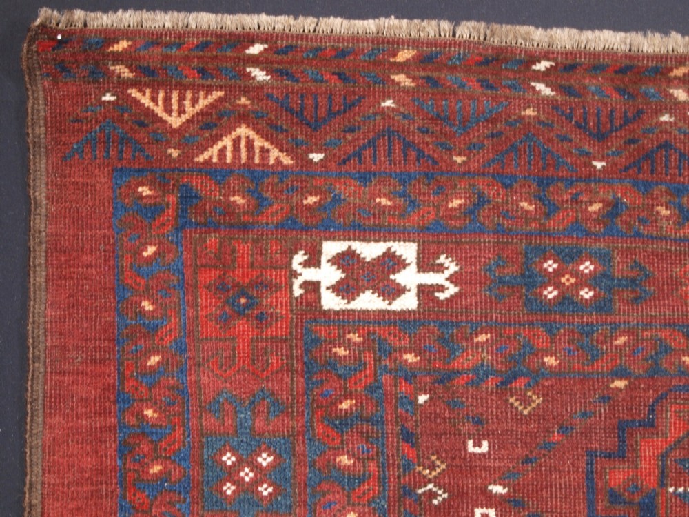 A rectangular hand-knotted antique Ersari Turkmen wool rug featuring twelve octagonal gul motifs on a deep red field with geometric borders. View IV