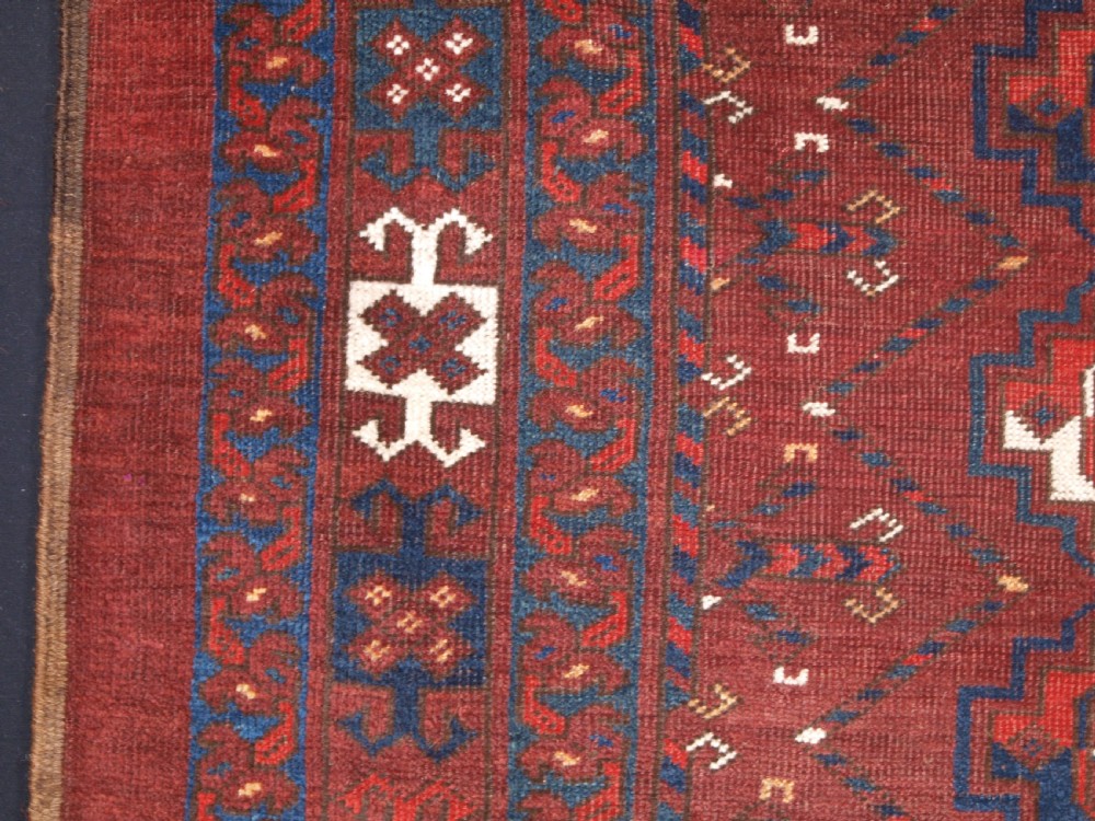 A rectangular hand-knotted antique Ersari Turkmen wool rug featuring twelve octagonal gul motifs on a deep red field with geometric borders. View V