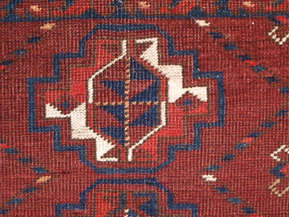 A rectangular hand-knotted antique Ersari Turkmen wool rug featuring twelve octagonal gul motifs on a deep red field with geometric borders. View VI