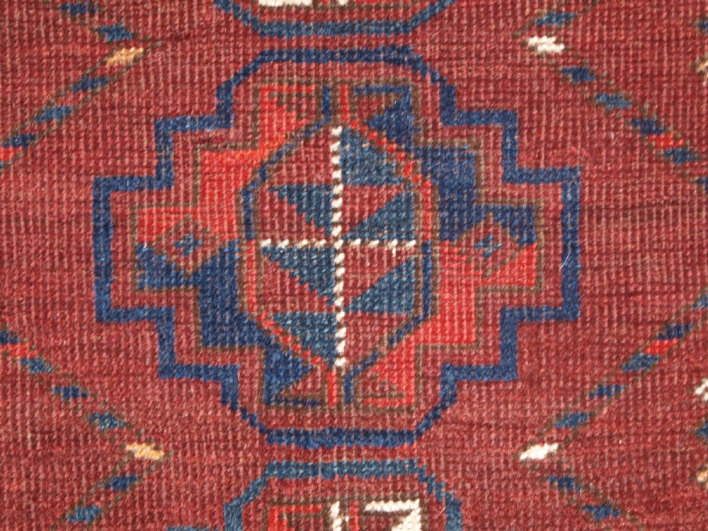 A rectangular hand-knotted antique Ersari Turkmen wool rug featuring twelve octagonal gul motifs on a deep red field with geometric borders. View VII