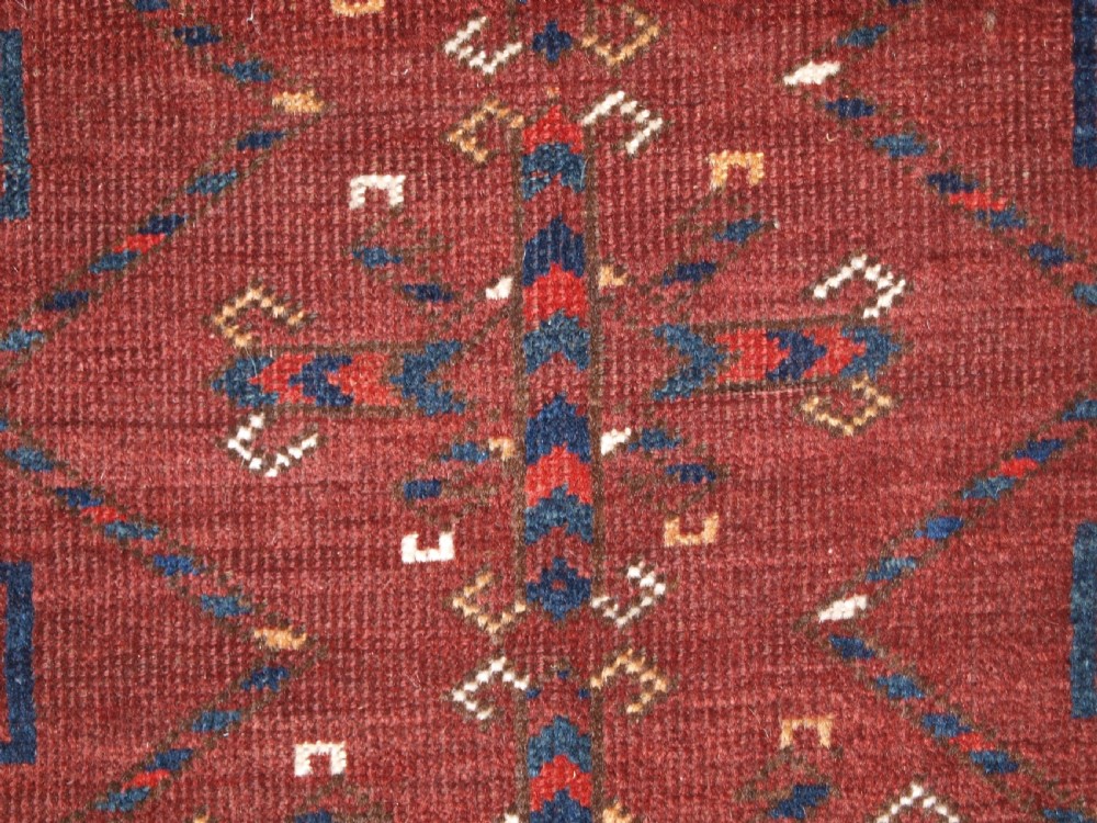 A rectangular hand-knotted antique Ersari Turkmen wool rug featuring twelve octagonal gul motifs on a deep red field with geometric borders. View X