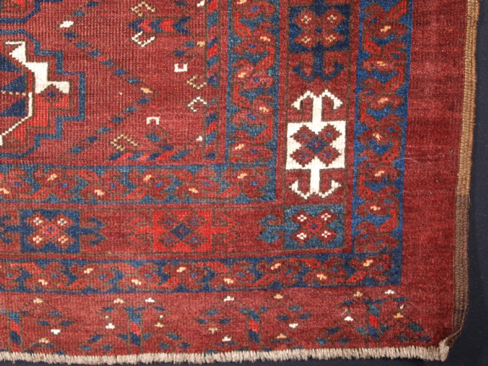A rectangular hand-knotted antique Ersari Turkmen wool rug featuring twelve octagonal gul motifs on a deep red field with geometric borders. View XI