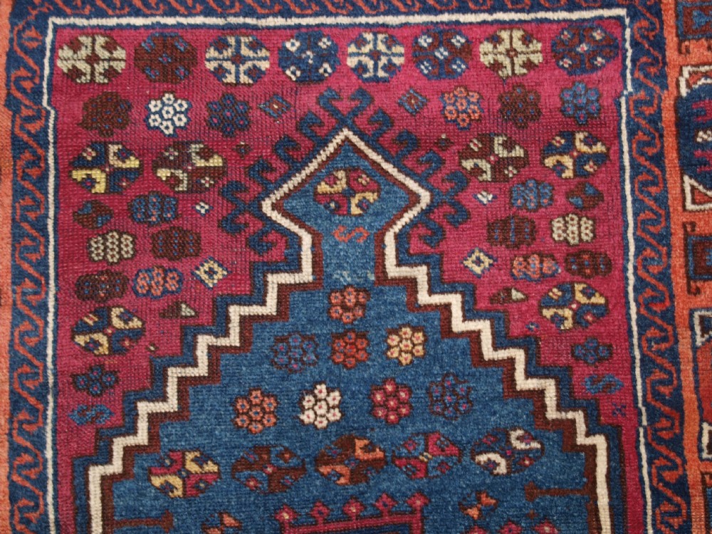 An antique East Anatolian Yuruk hand-knotted wool prayer rug featuring a blue central arched niche surrounded by magenta and terracotta geometric borders. View X