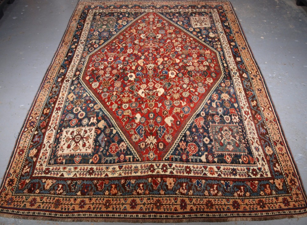 An antique hand-knotted Qashqai Kashkuli wool rug featuring a central red diamond medallion framed by complex floral motifs and multi-band geometric borders.