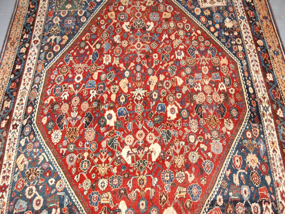 An antique hand-knotted Qashqai Kashkuli wool rug featuring a central red diamond medallion framed by complex floral motifs and multi-band geometric borders. View IV