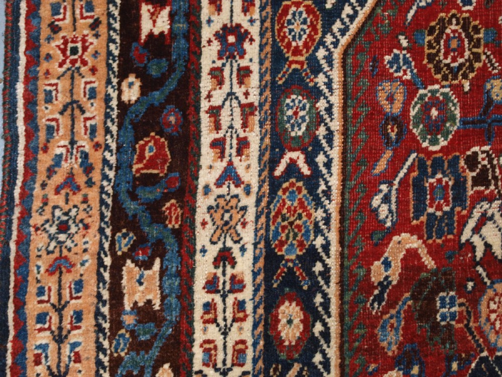 An antique hand-knotted Qashqai Kashkuli wool rug featuring a central red diamond medallion framed by complex floral motifs and multi-band geometric borders. View VII