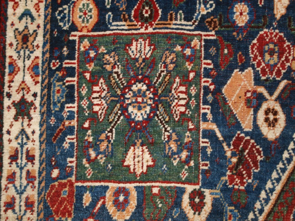 An antique hand-knotted Qashqai Kashkuli wool rug featuring a central red diamond medallion framed by complex floral motifs and multi-band geometric borders. View VIII