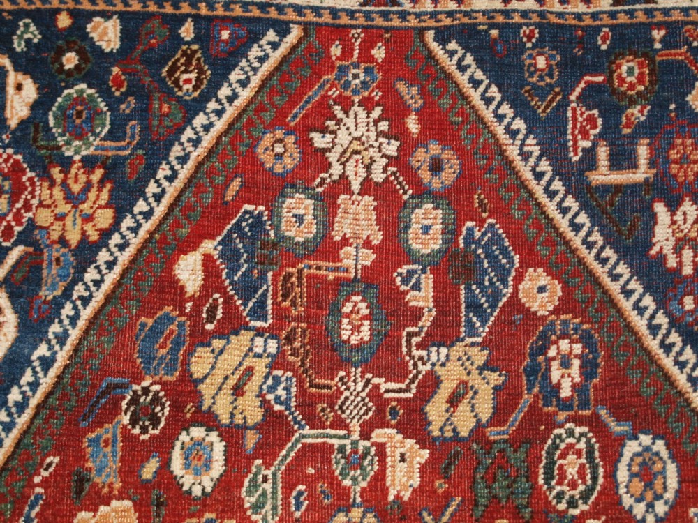 An antique hand-knotted Qashqai Kashkuli wool rug featuring a central red diamond medallion framed by complex floral motifs and multi-band geometric borders. View IX