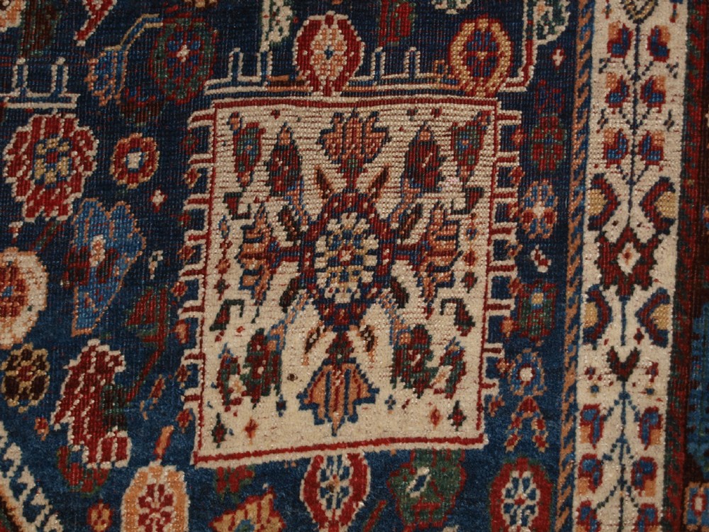 An antique hand-knotted Qashqai Kashkuli wool rug featuring a central red diamond medallion framed by complex floral motifs and multi-band geometric borders. View X