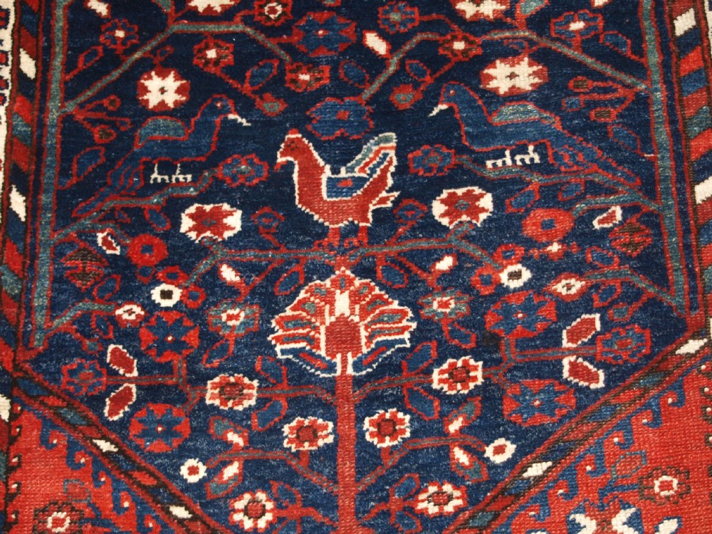 An antique hand-knotted Persian Luri rug featuring a dark navy field filled with stylised bird and floral motifs framed by a red surround and ivory floral border. View VIII