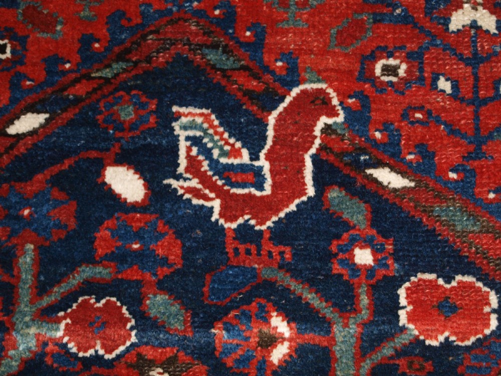 An antique hand-knotted Persian Luri rug featuring a dark navy field filled with stylised bird and floral motifs framed by a red surround and ivory floral border. View XI