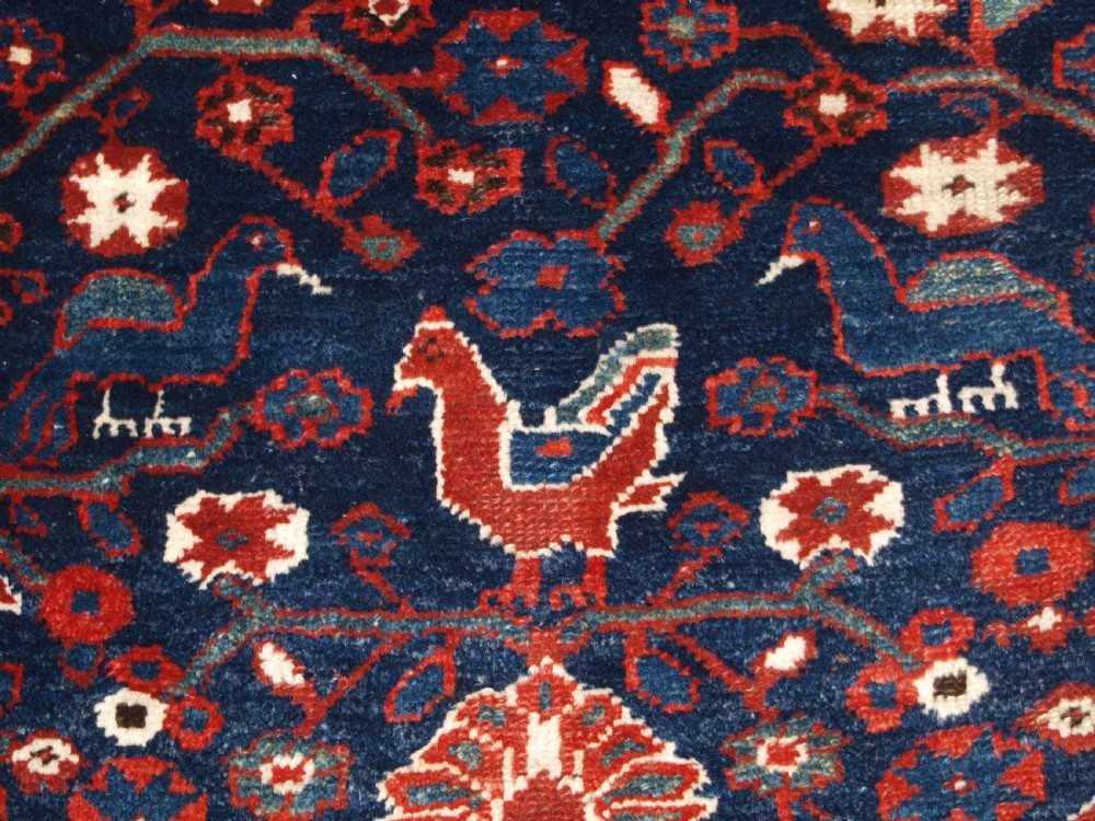 An antique hand-knotted Persian Luri rug featuring a dark navy field filled with stylised bird and floral motifs framed by a red surround and ivory floral border. View XII