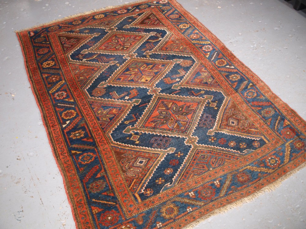 An antique hand-knotted wool Kurdish rug featuring three diamond medallion motifs down the centre on a deep blue field with geometric borders. View II