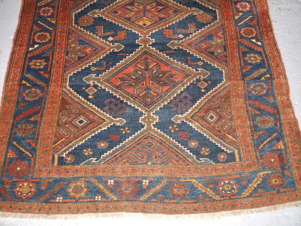 An antique hand-knotted wool Kurdish rug featuring three diamond medallion motifs down the centre on a deep blue field with geometric borders. View IV
