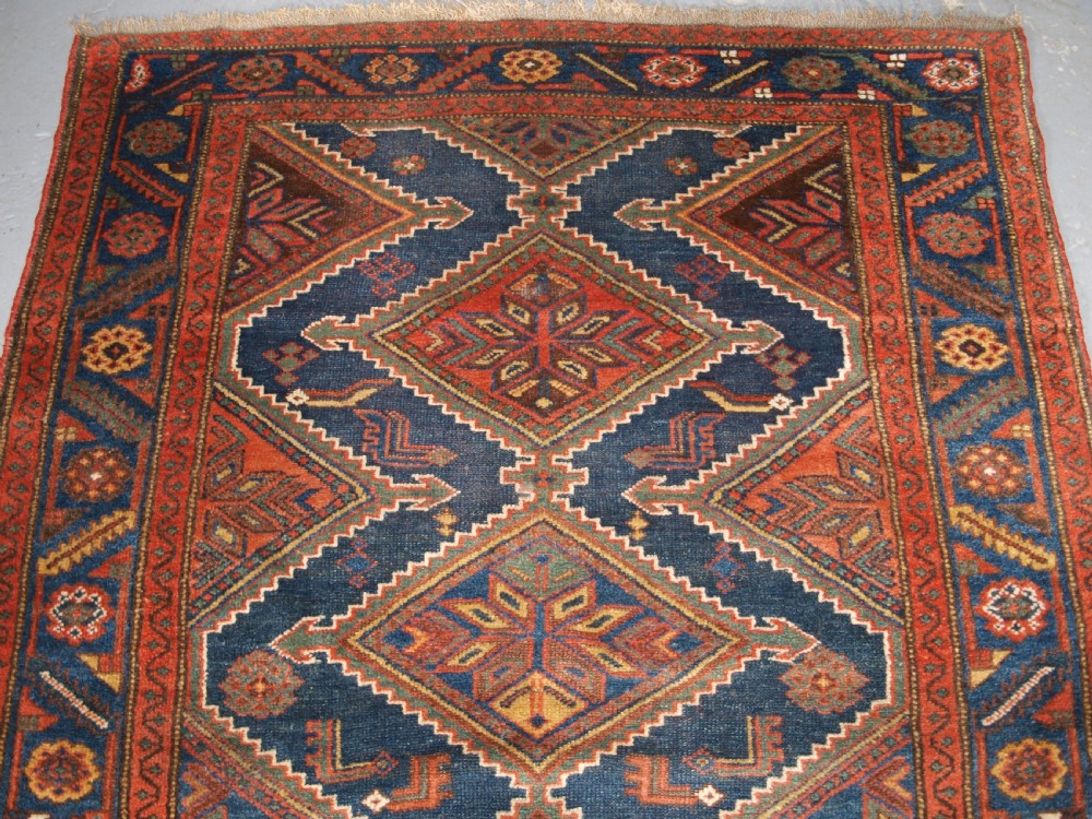 An antique hand-knotted wool Kurdish rug featuring three diamond medallion motifs down the centre on a deep blue field with geometric borders. View VI