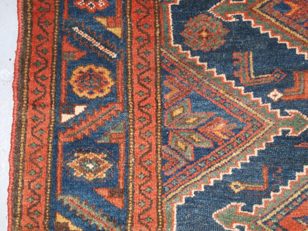 An antique hand-knotted wool Kurdish rug featuring three diamond medallion motifs down the centre on a deep blue field with geometric borders. View VII