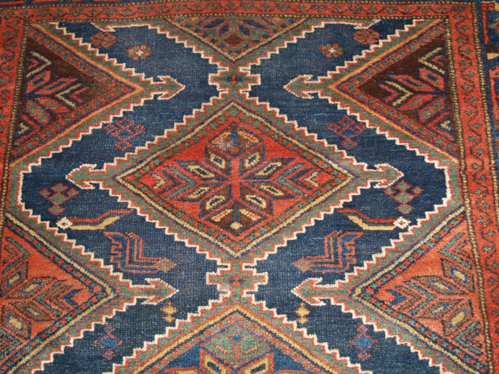 An antique hand-knotted wool Kurdish rug featuring three diamond medallion motifs down the centre on a deep blue field with geometric borders. View VIII