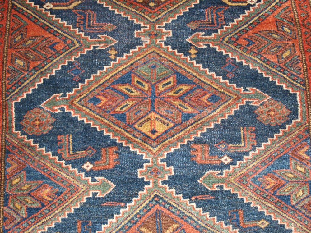 An antique hand-knotted wool Kurdish rug featuring three diamond medallion motifs down the centre on a deep blue field with geometric borders. View IX