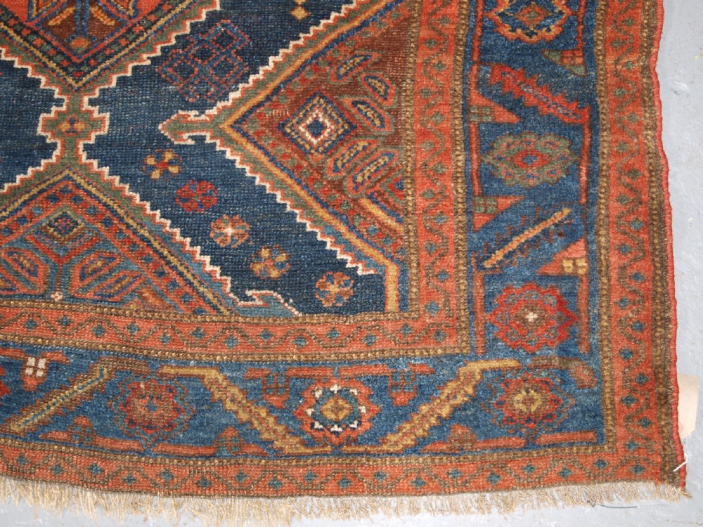 An antique hand-knotted wool Kurdish rug featuring three diamond medallion motifs down the centre on a deep blue field with geometric borders. View XI