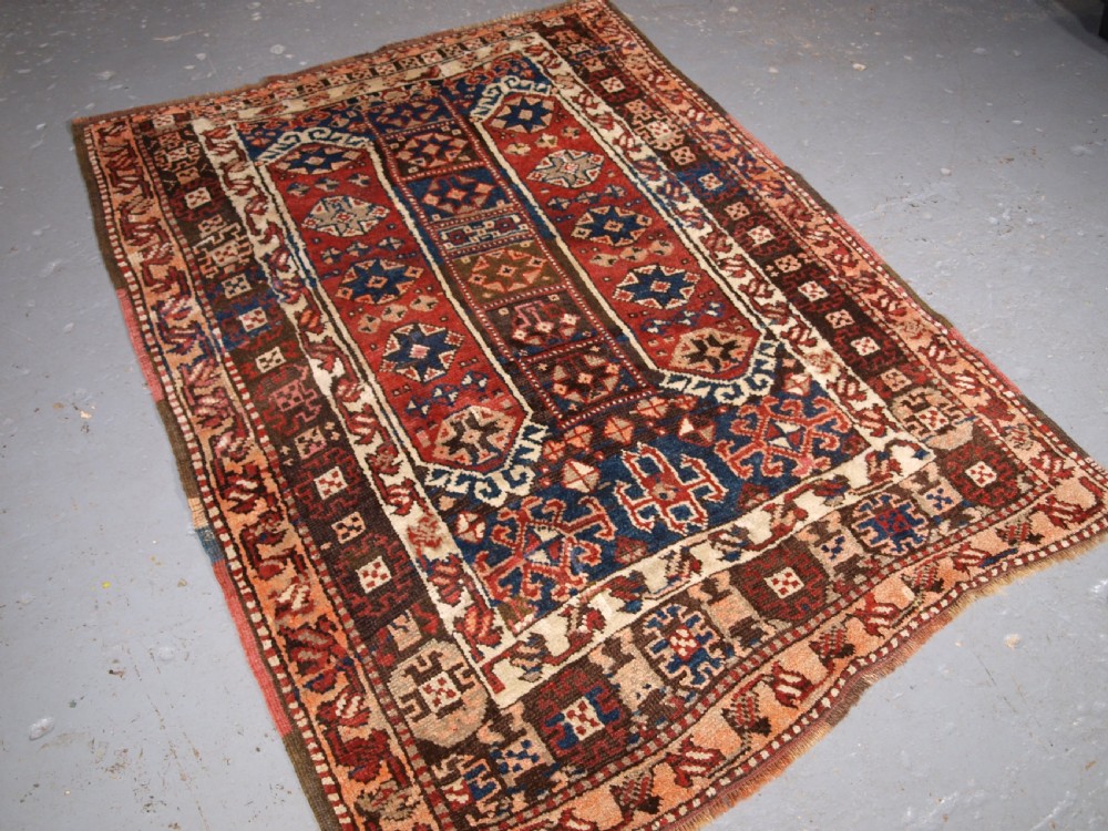An antique Turkish Bergama rug featuring hand-knotted geometric motifs in shades of terracotta red, navy blue, and cream.
