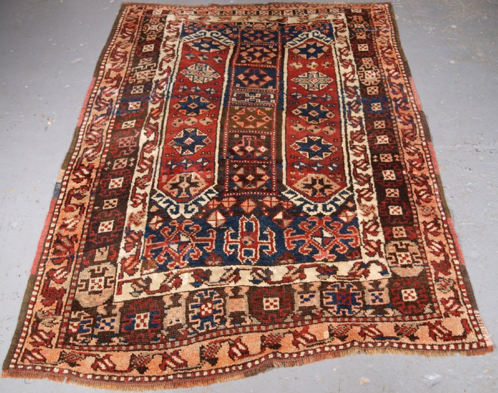 An antique Turkish Bergama rug featuring hand-knotted geometric motifs in shades of terracotta red, navy blue, and cream. View II
