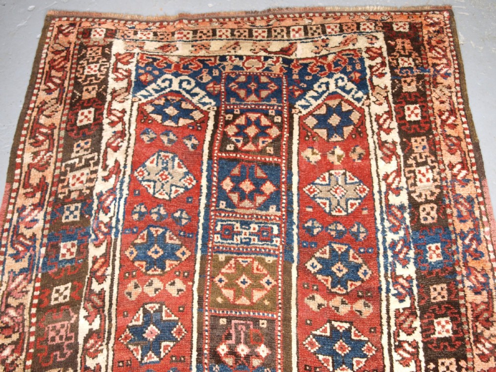 An antique Turkish Bergama rug featuring hand-knotted geometric motifs in shades of terracotta red, navy blue, and cream. View III