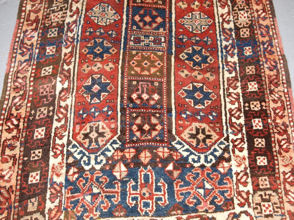 An antique Turkish Bergama rug featuring hand-knotted geometric motifs in shades of terracotta red, navy blue, and cream. View IV