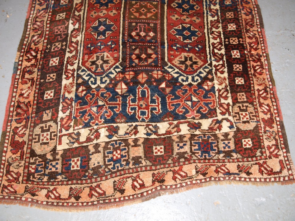 An antique Turkish Bergama rug featuring hand-knotted geometric motifs in shades of terracotta red, navy blue, and cream. View V