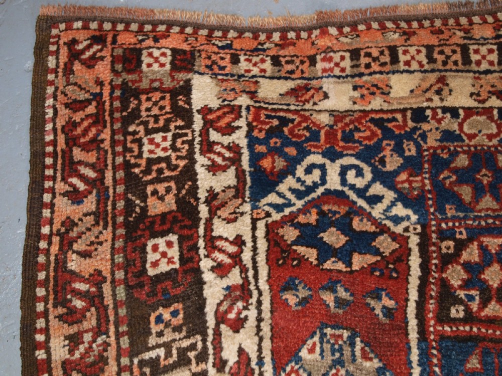 An antique Turkish Bergama rug featuring hand-knotted geometric motifs in shades of terracotta red, navy blue, and cream. View VI
