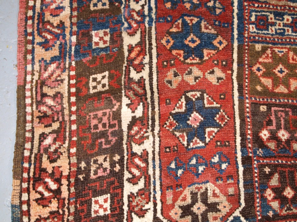 An antique Turkish Bergama rug featuring hand-knotted geometric motifs in shades of terracotta red, navy blue, and cream. View VII