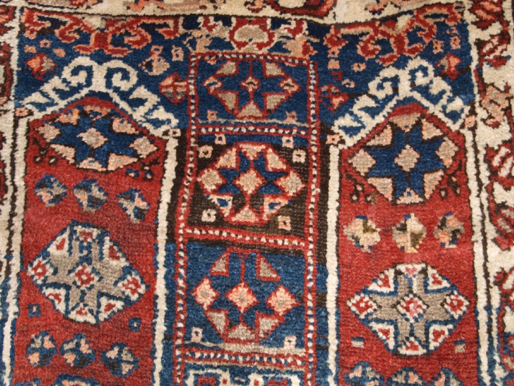 An antique Turkish Bergama rug featuring hand-knotted geometric motifs in shades of terracotta red, navy blue, and cream. View VIII