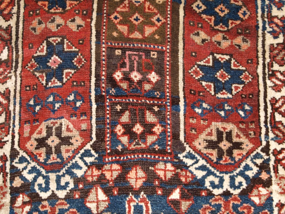 An antique Turkish Bergama rug featuring hand-knotted geometric motifs in shades of terracotta red, navy blue, and cream. View XI