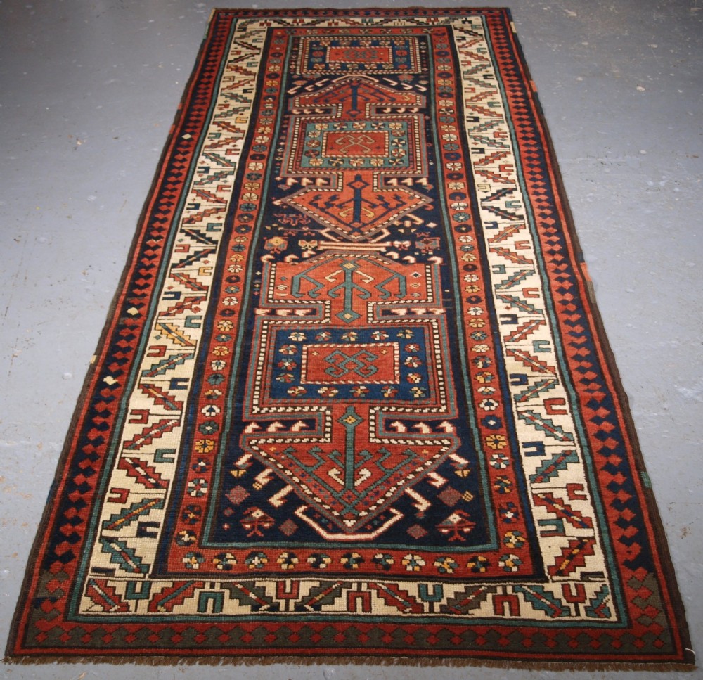 An antique hand-knotted wool Kelardasht runner rug featuring geometric medallions in dark blue, terracotta red, and cream with multi-layered patterned borders.