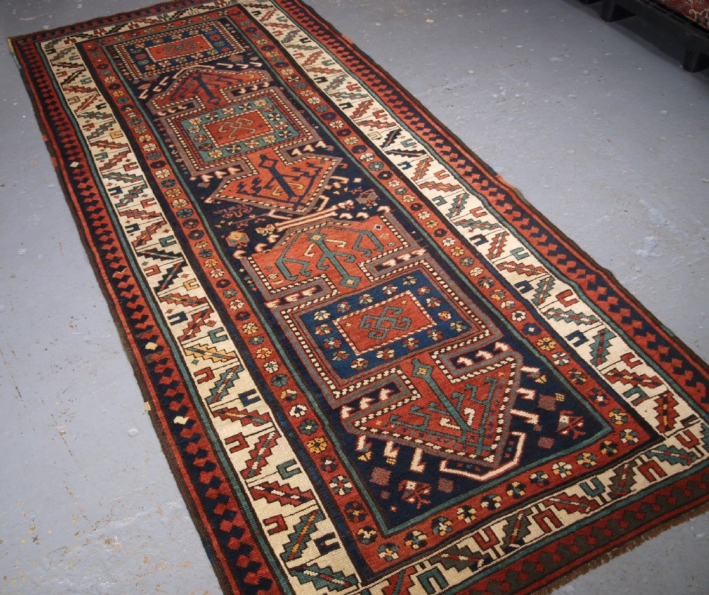 An antique hand-knotted wool Kelardasht runner rug featuring geometric medallions in dark blue, terracotta red, and cream with multi-layered patterned borders. View II