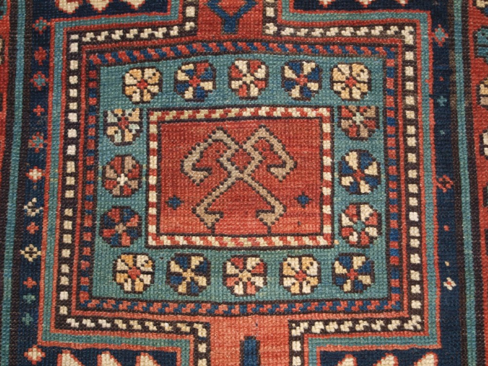 An antique hand-knotted wool Kelardasht runner rug featuring geometric medallions in dark blue, terracotta red, and cream with multi-layered patterned borders. View X