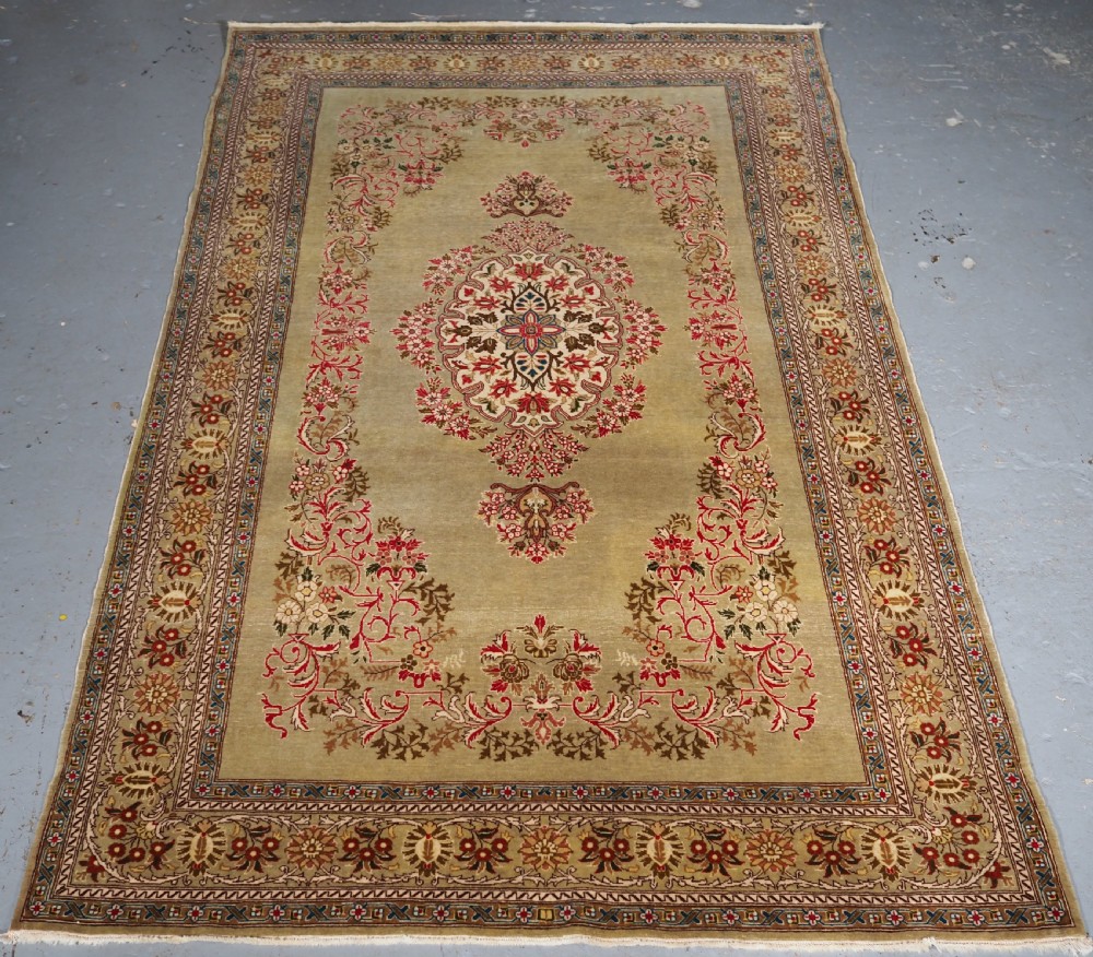 ANTIQUE TURKISH HEREKE WOOL RUG WITH SCARCE GREEN GROUND, CIRCA 1900/20.