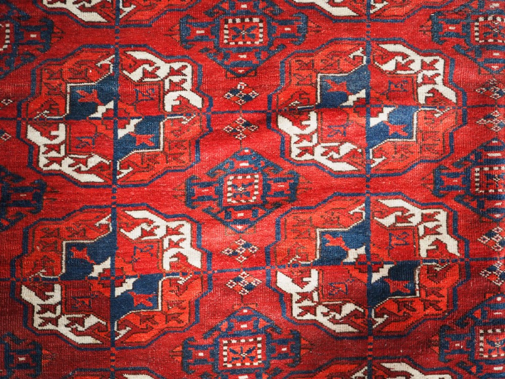 A large hand-knotted antique Tekke Turkmen main carpet in deep red featuring a four by ten grid of octagonal gul motifs framed by detailed geometric borders. View V