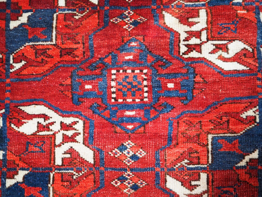 A large hand-knotted antique Tekke Turkmen main carpet in deep red featuring a four by ten grid of octagonal gul motifs framed by detailed geometric borders. View VII
