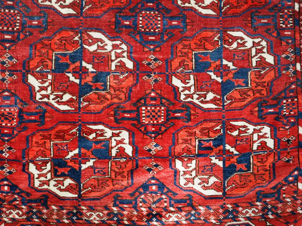 A large hand-knotted antique Tekke Turkmen main carpet in deep red featuring a four by ten grid of octagonal gul motifs framed by detailed geometric borders. View VIII