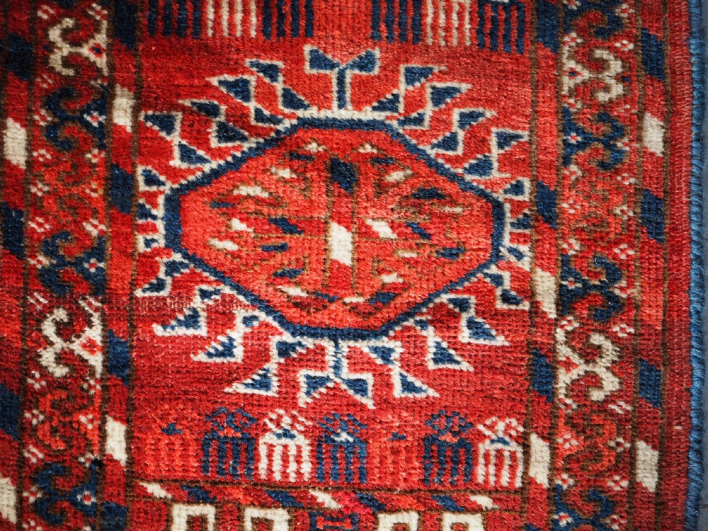 A large hand-knotted antique Tekke Turkmen main carpet in deep red featuring a four by ten grid of octagonal gul motifs framed by detailed geometric borders. View XII