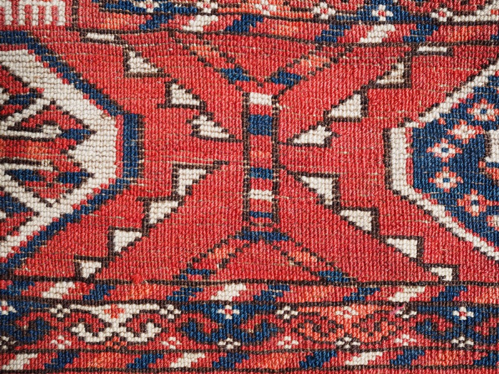 A large hand-knotted antique Tekke Turkmen main carpet in deep red featuring a four by ten grid of octagonal gul motifs framed by detailed geometric borders. View XIV